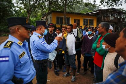 Policías hondureños hablan con un grupo de migrantes en Ceibita, Honduras. Medios locales reportaron que los agentes impedían el cruce a territorio guatemalteco de quienes no llevaran pruebas de no tener coronavirus o llevaran a menores sin documentos a su cargo.