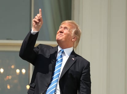 Donald Trump señala al sol, sin las gafas de protección, durante el eclipse de sol, desde el balcón de la Casa Blanca.