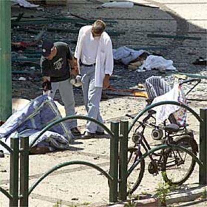 Un policía israelí levanta una manta para ver a una de las víctimas de la bomba, ayer en Netania.