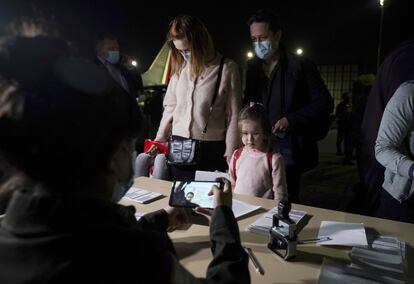 El mexicano Ulises García, su esposa Viktoriia Polishuk, de Ucrania, y su hija Paula García presentan sus pasaportes en un control de migración en el aeropuerto de la Ciudad de México, tras llegar en el vuelo de evacuación este viernes.