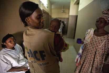 Acción contra el hambre lleva trabajando en Malí desde 1996 para luchar contra la desnutrición. En la imagen, una de sus miembros sostiene a un niño en un centro de Bamako.