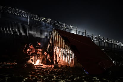 Una familia se calienta en una fogata a las puertas de una tienda de campaña en la frontera entre la franja de Gaza y Egipto, el 27 de febrero de 2024. 