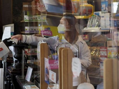 Una persona es atendida por una trabajadora de una farmacia de Vitoria en plena pandemia.