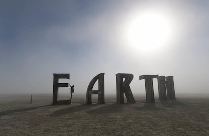 Una participante se cuelga de la letra E de la palabra Earth (Tierra), una de las esculturas del desierto de Black Rock, en Nevada, por el festival Burning Man.