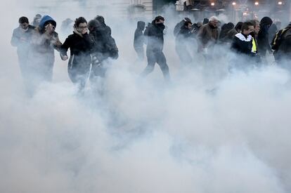 Los manifestantes corren para ponerse a resguardo del gas lacrimógeno lanzado por la policía, en París.