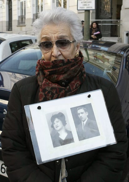 Una mujer, que porta las fotos de sus padres fusilados durante la Guerra Civil, espera la llegada de Baltasar Garzn al Tribunal Supremo.