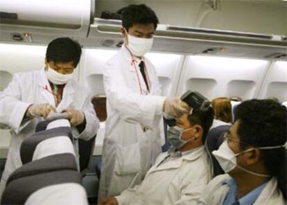 Los médicos toman la temperatura a un grupo de pasajeros de un vuelo procedente de Hong Kong, hoy en Shangai.