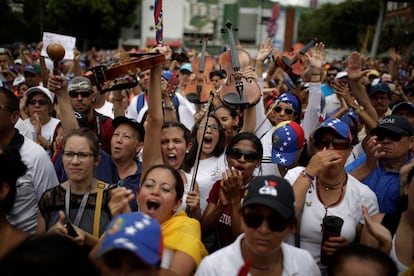 Jóvenes músicos levantan sus violines durante una concentración para rendir homenaje a las víctimas de violencia durante las protestas contra el presidente Nicolás Maduro, el 7 de mayo de 2017, en Caracas.