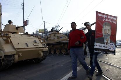 Partidarios del islamista egipcio Mohamed Morsi pasean frente a los tanques del ej&eacute;rcito egipcio desplegados cerca del palacio presidencial en El Cairo.