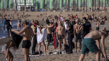 Agentes de la policía piden a los ciudadanos no tumbarse en la playa de la Barceloneta, este miércoles.