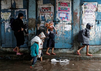 Una mujer acompaña a tres niños en una calle inundada debido a las lluvias del monzón en Bombay (India).