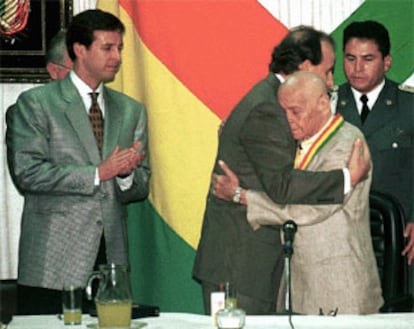 Hugo Banzer (derecha) es felicitado por el ministro de Educación Tito Oz De Vila mientras observa a la izquierda el Vice presidente Jorge Quiroga