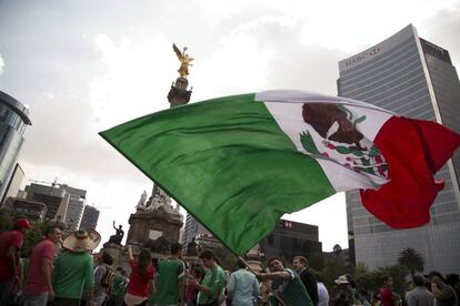 Un aficionado mexicano ondea una bandera mexicana en la Glorieta del Ángel de la Independencia, en la Ciudad de México.