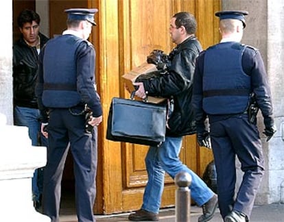 Un policía entra en el cuartel general de la policía en París con diverso material incautado a los detenidos.