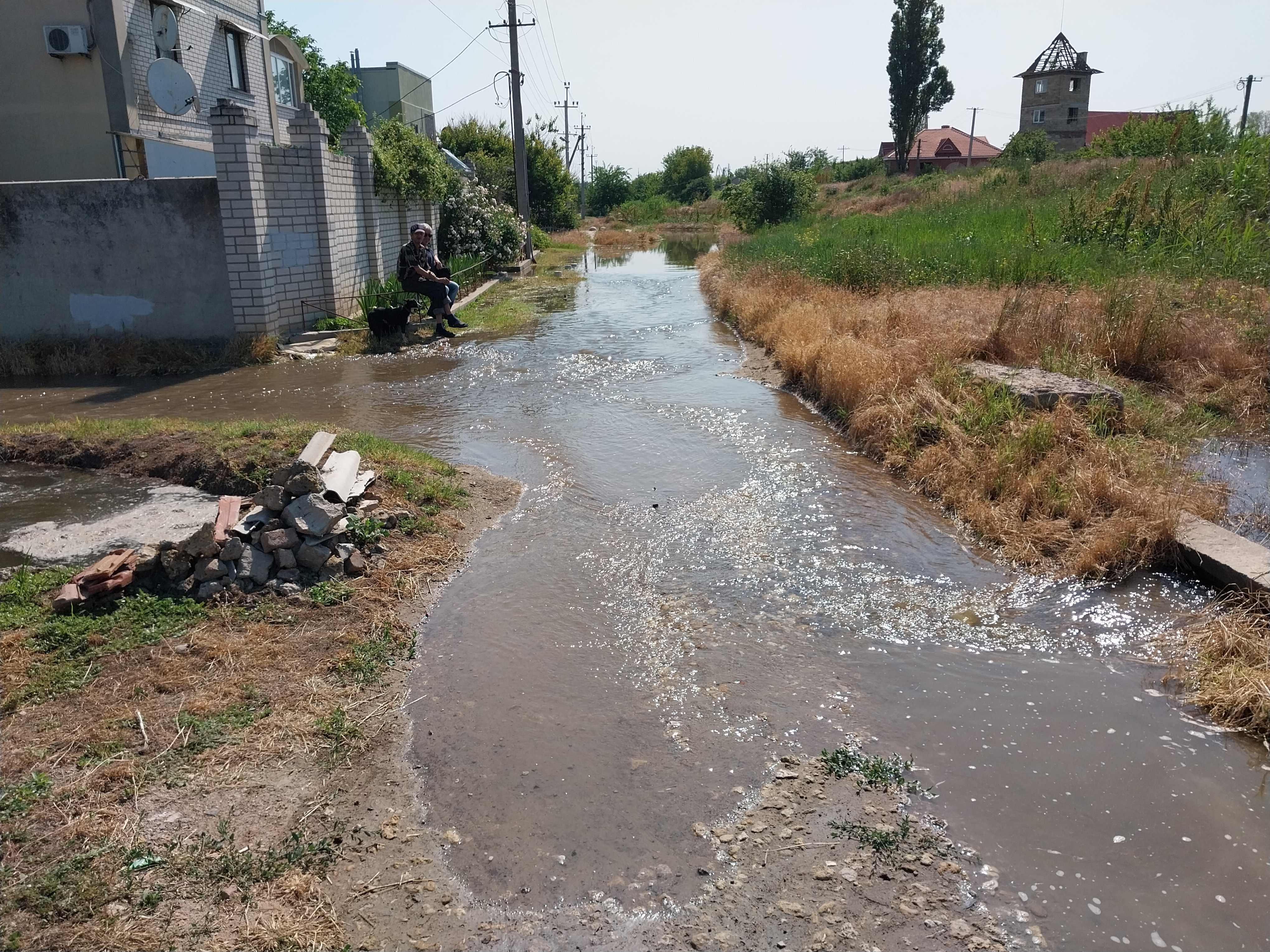 Un hombre mira correr el agua sentado en un banco a las afueras de Jersón, parcialmente inundado tras la rotura de la presa.