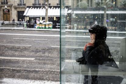 Una mujer se refugia de la nieve en una cabina telefónica de París, Francia, el 12 de marzo de 2013.