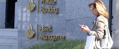 Una mujer camina delante de la sede de Santander Asset Management.