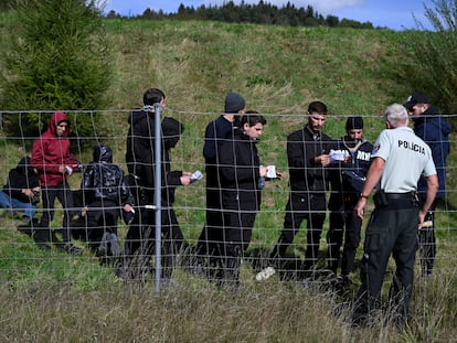 Un agente de policía controla a un grupo de migrantes a 10 kilómetros de la frontera entre Eslovaquia y Polonia, cerca de la aldea eslovaca de Cierne, este miércoles.