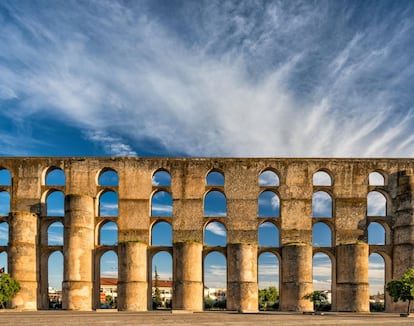 Los habitantes de Elvas, en el Alentejo portugués, tienen por costumbre ir de compras a los grandes almacenes de Badajoz. Y es que apenas 15 kilómetros separan ambas ciudades. Elvas sigue siendo, a día de hoy, una parada imprescindible cuando se entra en Portugal en coche, camino de Lisboa, desde la frontera pacense. La ciudad portuguesa presume de contar con la mayor colección de fortificaciones en baluarte del mundo, que son prueba de una sofisticada tecnología militar. Los fosos, el fuerte y las robustas murallas subrayan su importancia estratégica, tan cerca de España. Fue declarada Patrimonio Mundial en 2012. Aunque no hay mucho para mantener la atención más de un día, Elvas es un lugar interesante para visitar, con un evocador ambiente de urbe fronteriza, calles estrechas e imponentes murallas. Dentro de éstas hay una plaza encantadora, museos insólitos y no muchos turistas. Una de las piezas claves es el Aqueduto da Amoreira, que tardó casi 100 años en construirse a finales del siglo XVI. Y no sorprende, porque es impresionante con sus enormes contrafuertes cilíndricos y varios pisos de arcos que comienzan 7 kilómetros al oeste de la ciudad y llevan agua a la fuente de mármol de Largo da Misericórdia.