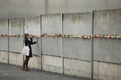 Una mujer fotografía de cerca las rosas que han dejado en conmemoración de la caída del Muro.