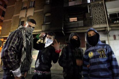 Jóvenes embozados, ayer en las calles de Salt ante una fachada chamuscada por uno de los incendios del fin de semana.