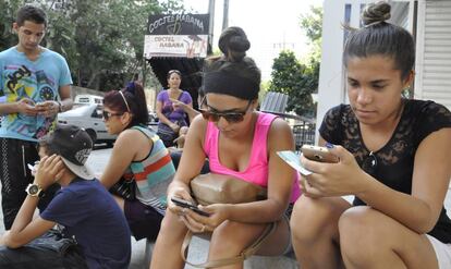 Doa j&oacute;venes navegan en Internet con el tel&eacute;fono m&oacute;vil en La Habana, Cuba.