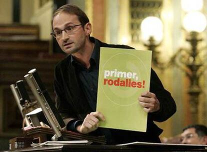 El diputado de ICV Joan Herrera muestra un cartel que dice <b>"Primero, cercanías".</b>
La