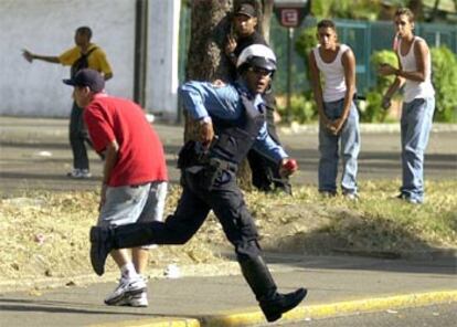 Un oficial de la policía de Caracas corre para intentar separar a manifestantes chavistas y opositores.