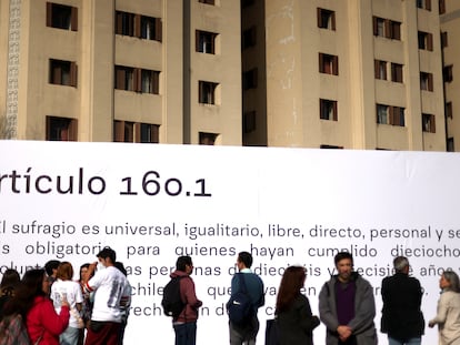 Un grupo de personas pasea frente a una gigantografía con un artículo de la Constitución propuesta en Chile, este martes en Santiago.
