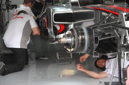 Mecánicos del equipo McLaren trabajan en el coche de Button.