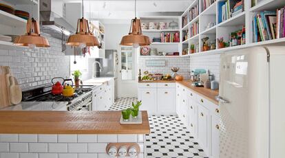 Dos ideas organizan la cocina: sustituir los armarios superiores por estanterías y utilizar el mosaico de azulejos (de Via Ceramica) para ir abriendo el espacio hacia el salón. La madera de las encimeras y las lámparas de bronce, adquiridas en un anticuario francés, añaden calidez. Los fogones y la nevera son de Smeg.  