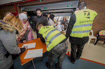 Varios pasajeros se registran ante dos empleados en un polideportivo donde se concentran los viajeros en Zaventem, cerca de Bruselas.