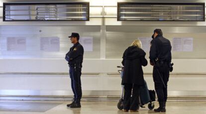 Un  policía informa a una viajera frente a los mostradores de Air Comet, ya sin rótulos.