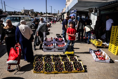 Varias personas pasan junto a un puesto callejero de frutas y verduras cerca de la puerta de Damasco en Jerusalén, este viernes.