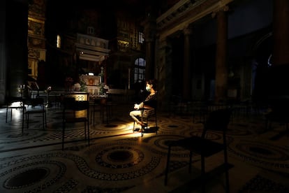 Una mujer se sienta entre las sillas colocadas en la basílica de Santa María en Trastevere, Roma (Italia).