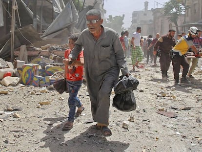 Un grupo de voluntarios de los 'cascos blancos' llevan a un hombre herido en camilla tras un ataque aéreo en la ciudad de Maaret al-Numan, en la provincia de Idlib (Siria).