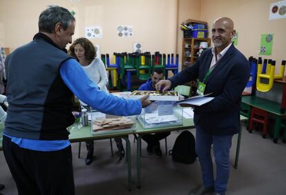 El miembro de una de las mesas electorales del colegio La Navata, ubicado en Galapagar, reparte bombones al comienza de la jornada electoral.