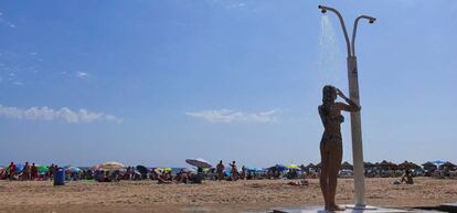 Una joven se refresca en una de las duchas instaladas en la playa de la Malvarrosa de Valencia.