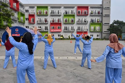TOPSHOT - Indonesian doctors, nurses and volunteers conduct morning workouts along with patients of the COVID-19 with light symptoms (at balconies) at the quarantine house of the COVID-19 in Tangerang on June 15, 2020. (Photo by ADEK BERRY / AFP)