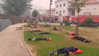 13 bomberos descansando sobre la hierba en la aldea de Álvares.