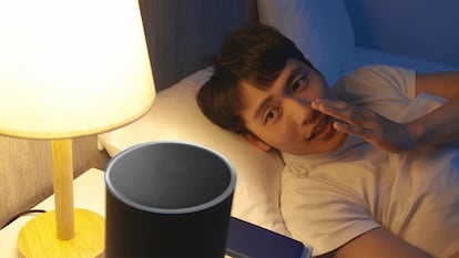 Un hombre comunicándose con Alexa desde la cama.