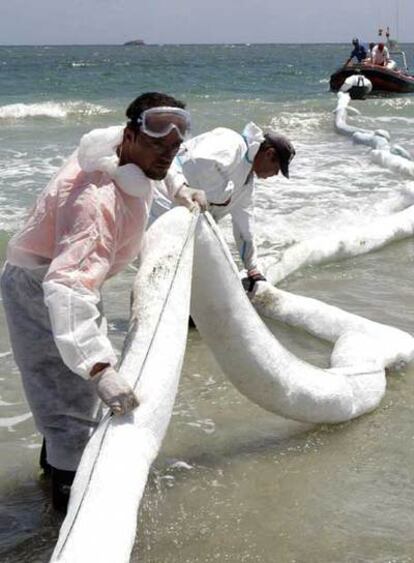Operarios colocan barreras absorbentes en la playa ibicenca de En Bossa para contener el fuel.