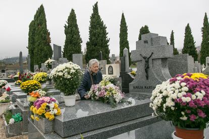 Una mujer deja un ramo de flores sobre una tumba del cementerio de Manzanares el Real (Madrid). 