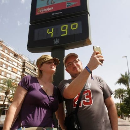 Turistas se hacen una foto junto a un termómetro de Córdoba que marca 49ºC debido a la ola de calor que en los próximos días dejarán temperaturas extremas en la Península y Baleares.