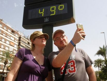 Turistas se hacen una foto junto a un termómetro de Córdoba que marca 49ºC debido a la ola de calor que en los próximos días dejarán temperaturas extremas en la Península y Baleares.