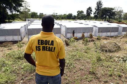 Un hombre en cuya camiseta se lee &#039;El &eacute;bola es real&#039; mira hacia un nuevo centro de tratamiento creado en Monrovia (Liberia) este domingo.