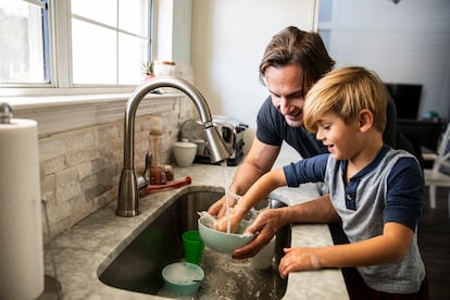 Un padre friega los platos con su hijo-