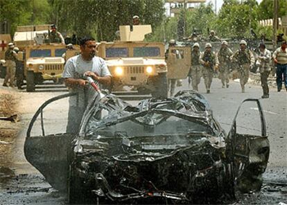 Un bombero iraquí extingue el fuego de un vehículo calcinado por la explosión de un coche bomba en el centro de Bagdad.