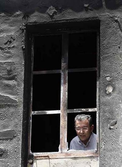 Paulino Rivero mira los efectos del fuego desde la ventana de una casa incendiada en Tenerife.