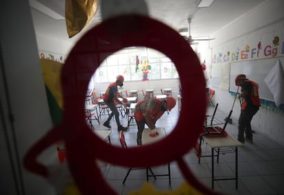 Trabajadores limpian un aula en un colegio público de Ciudad de México. La reanudación de las clases presenciales se produce tras haberse finalizado la vacunación a docentes este pasado sábado.